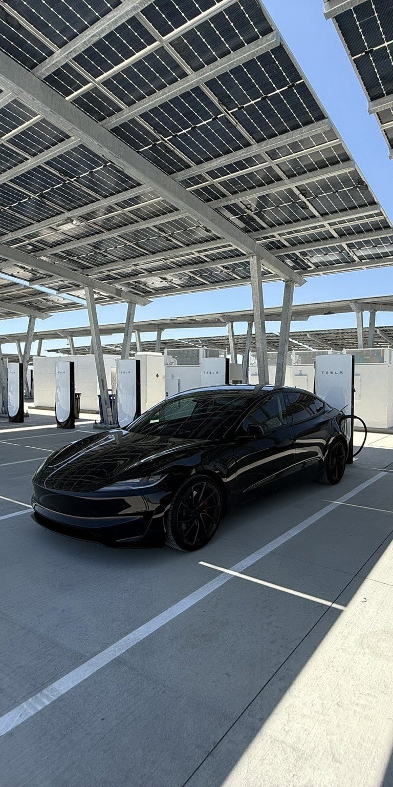 Tesla charging beneath a solar canopy at a Supercharger site