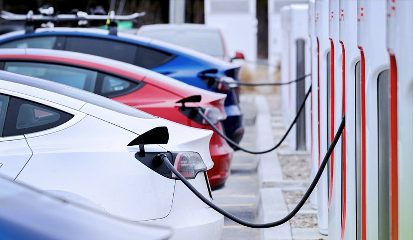 Electric vehicles charging at a row of fast chargers